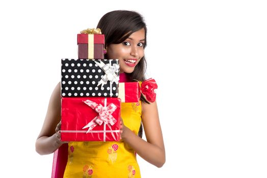 Portrait of young happy smiling Indian Girl holding gift boxes on a white background.