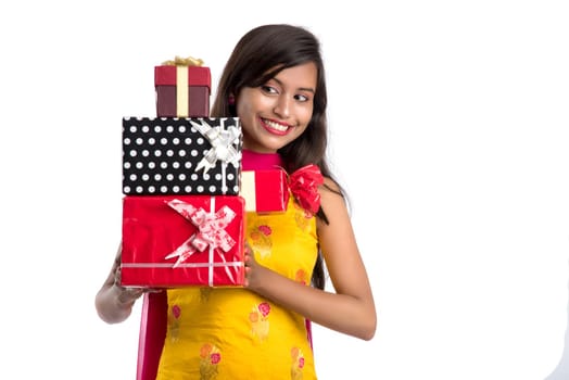 Portrait of young happy smiling Indian Girl holding gift boxes on a white background.