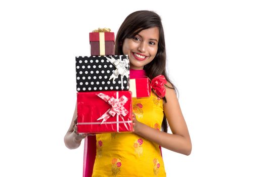 Portrait of young happy smiling Indian Girl holding gift boxes on a white background.