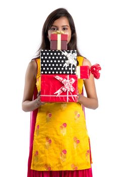 Portrait of young happy smiling Indian Girl holding gift boxes on a white background.