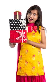 Portrait of young happy smiling Indian Girl holding gift boxes on a white background.