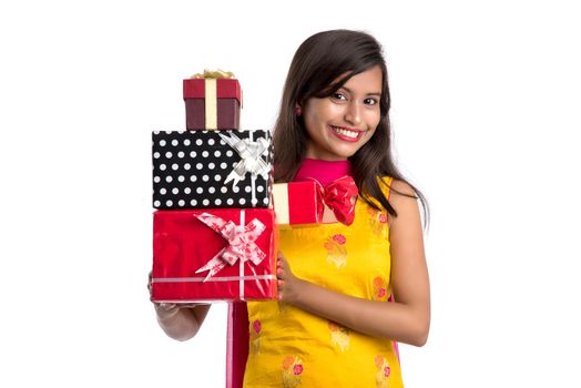 Portrait of young happy smiling Indian Girl holding gift boxes on a white background.