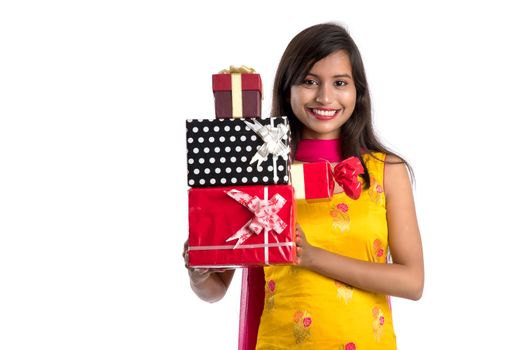 Portrait of young happy smiling Indian Girl holding gift boxes on a white background.