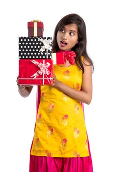 Portrait of young happy smiling Indian Girl holding gift boxes on a white background.