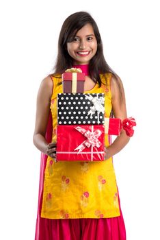 Portrait of young happy smiling Indian Girl holding gift boxes on a white background.