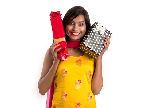 Portrait of young happy smiling Indian Girl holding gift boxes on a white background.