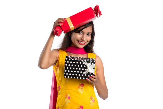 Portrait of young happy smiling Indian Girl holding gift boxes on a white background.