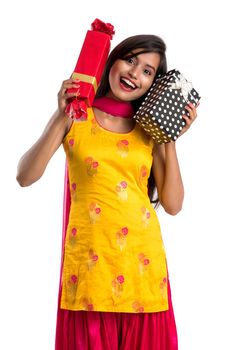 Portrait of young happy smiling Indian Girl holding gift boxes on a white background.