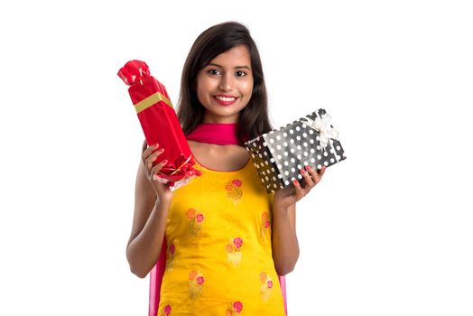 Portrait of young happy smiling Indian Girl holding gift boxes on a white background.