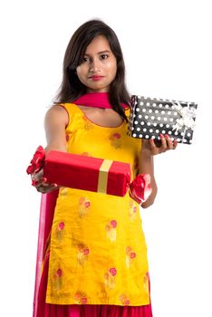 Portrait of young happy smiling Indian Girl holding gift boxes on a white background.