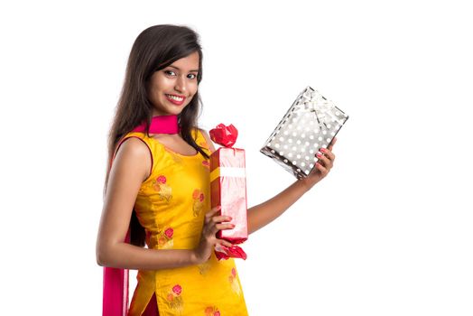 Portrait of young happy smiling Indian Girl holding gift boxes on a white background.