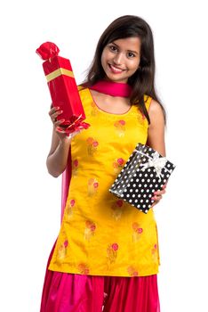 Portrait of young happy smiling Indian Girl holding gift boxes on a white background.