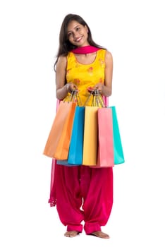 Beautiful Indian young girl holding and posing with shopping bags on a white background