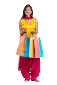 Beautiful Indian young girl holding and posing with shopping bags on a white background