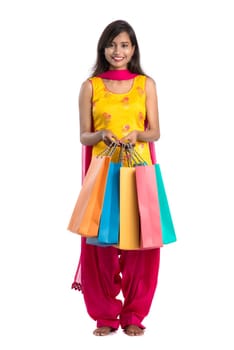 Beautiful Indian young girl holding and posing with shopping bags on a white background