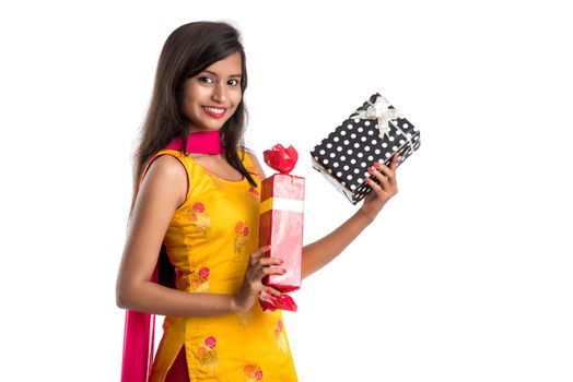 Portrait of young happy smiling Indian Girl holding gift boxes on a white background.