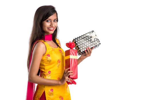 Portrait of young happy smiling Indian Girl holding gift boxes on a white background.