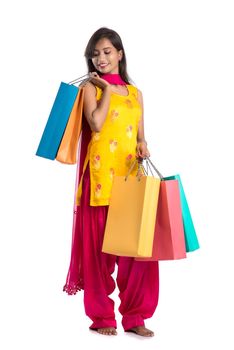 Beautiful Indian young girl holding and posing with shopping bags on a white background