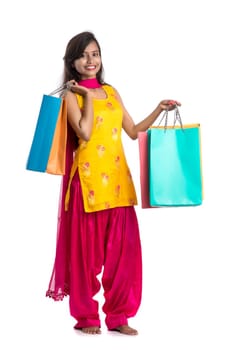 Beautiful Indian young girl holding and posing with shopping bags on a white background