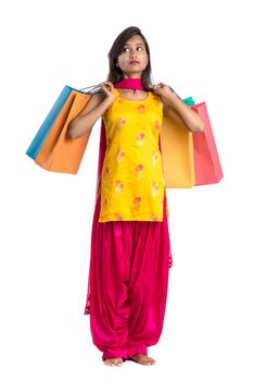 Beautiful Indian young girl holding and posing with shopping bags on a white background