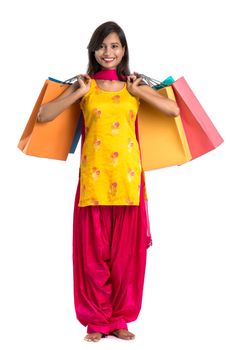 Beautiful Indian young girl holding and posing with shopping bags on a white background