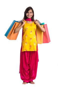 Beautiful Indian young girl holding and posing with shopping bags on a white background