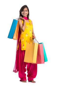 Beautiful Indian young girl holding and posing with shopping bags on a white background