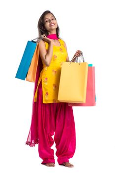 Beautiful Indian young girl holding and posing with shopping bags on a white background