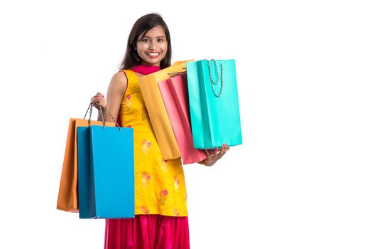 Beautiful Indian young girl holding and posing with shopping bags on a white background