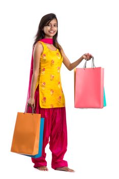 Beautiful Indian young girl holding and posing with shopping bags on a white background