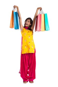 Beautiful Indian young girl holding and posing with shopping bags on a white background