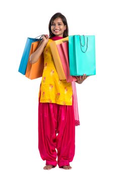 Beautiful Indian young girl holding and posing with shopping bags on a white background