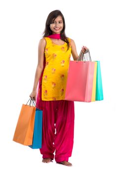 Beautiful Indian young girl holding and posing with shopping bags on a white background