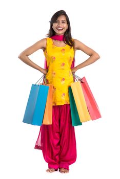 Beautiful Indian young girl holding and posing with shopping bags on a white background