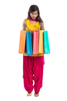 Beautiful Indian young girl holding and posing with shopping bags on a white background