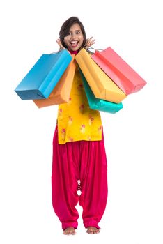 Beautiful Indian young girl holding and posing with shopping bags on a white background