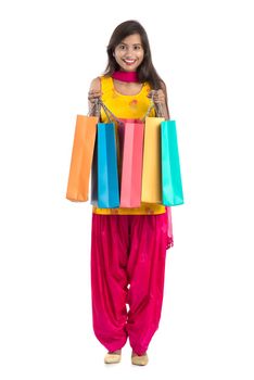 Beautiful Indian young girl holding and posing with shopping bags on a white background