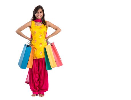 Beautiful Indian young girl holding and posing with shopping bags on a white background