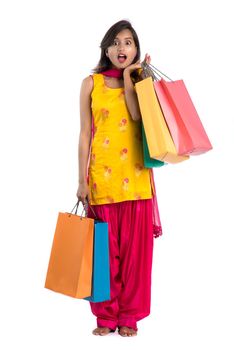 Beautiful Indian young girl holding and posing with shopping bags on a white background