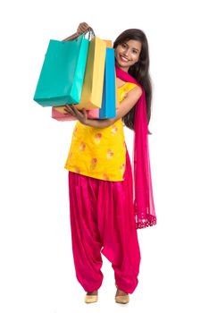 Beautiful Indian young girl holding and posing with shopping bags on a white background