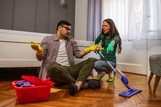 Man is lazy. His wife is telling him to continue cleaning their apartment.