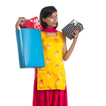 A beautiful woman posing with a shopping bag and gift Boxes on a white background.