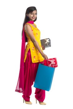 A beautiful woman posing with a shopping bag and gift Boxes on a white background.