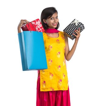 A beautiful woman posing with a shopping bag and gift Boxes on a white background.