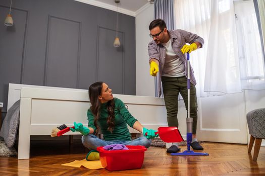 Woman is lazy. Man is telling her to continue cleaning their apartment.