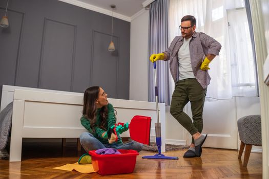 Woman is lazy. Man is telling her to continue cleaning their apartment.