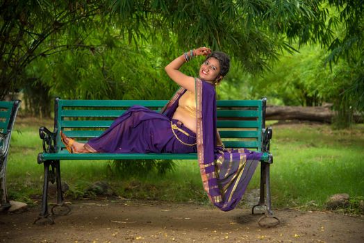 Beautiful Indian young girl in Traditional Saree posing outdoors