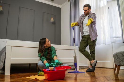 Woman is lazy. Man is telling her to continue cleaning their apartment.