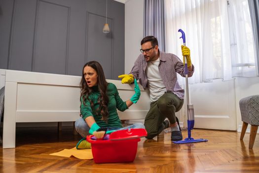 Woman is lazy. Man is telling her to continue cleaning their apartment.