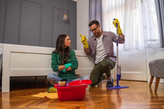 Woman is lazy. Man is telling her to continue cleaning their apartment.